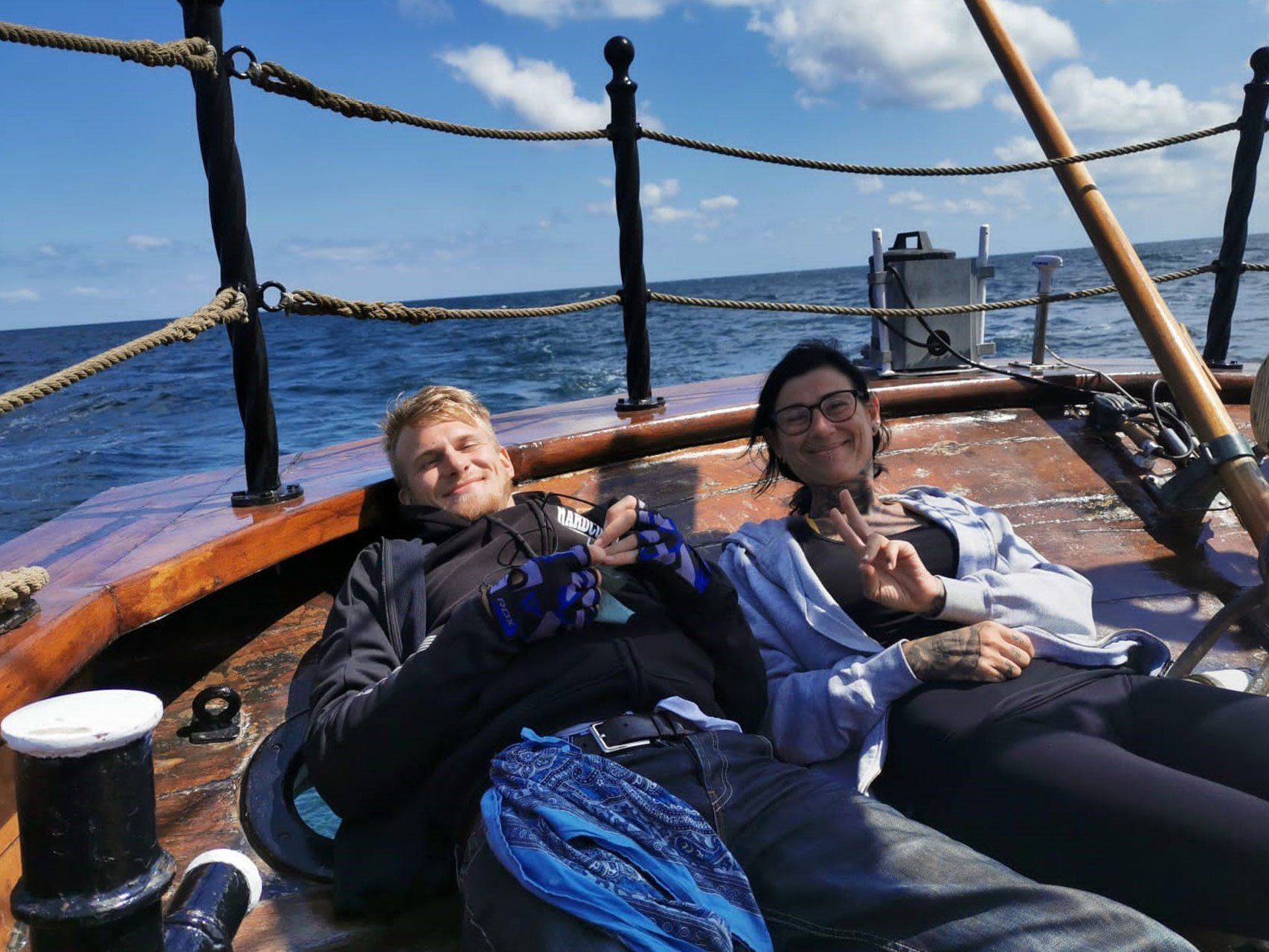 Eine junge Frau und ein junger Mann liegen an Deck eines Schiffs und genießen 