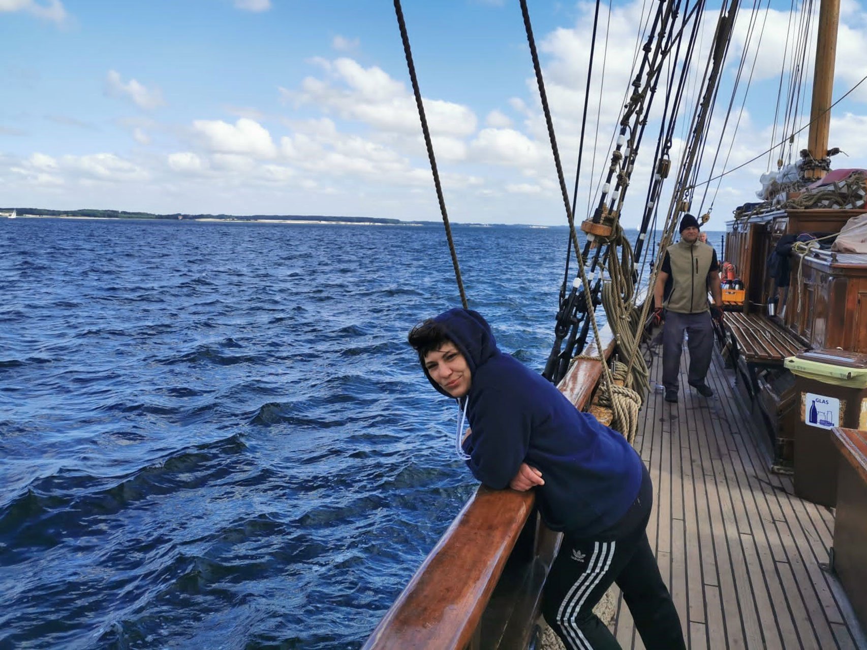 Eine junge Frau lehnt an der Reeling eines Segelschiffs