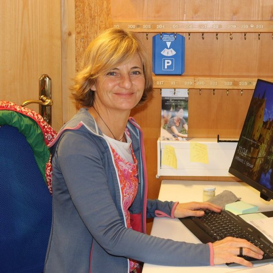 Büro: eine Frau am Computer lächelt in die Kamera