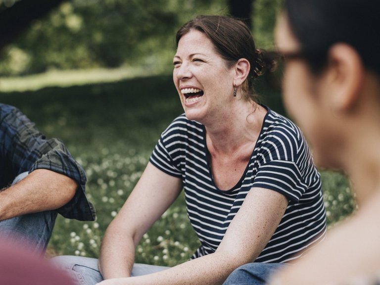 Nahaufnahme: Frauen und Männer sitzen auf einer Wiese und lachen