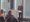 Ein Mann in einem dunklen Anzug steht hinter einem weißen Podium und hält eine Präsentation vor einem Publikum. Im Hintergrund sind große Fenster mit Jalousien zu sehen.